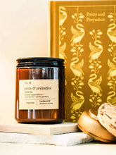 Load image into Gallery viewer, Candle labeled 'pride &amp; prejudice' with a book titled 'Pride and Prejudice' in the background.
