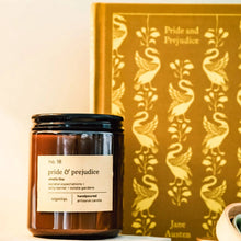 Load image into Gallery viewer, Candle labeled 'pride &amp; prejudice' next to a book titled 'Pride and Prejudice' with swan design.

