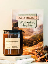 Load image into Gallery viewer, Candle labeled 'Wuthering Heights' by Emily Bronte with a book in the background

