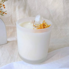 Load image into Gallery viewer, Sea Salt Caramel and Clear Quartz Candle in a white holder with decorative elements on a light background
